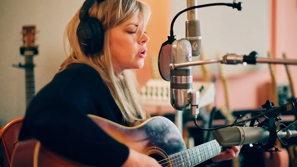 Photo of Courtney Patton with guitar and microphone
