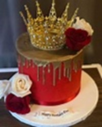 Photo of a red and gold frosted cake, with white and red roses, and a gold crown on top