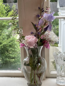 Photo of greens, white, pink and purple flowers in a glass vase