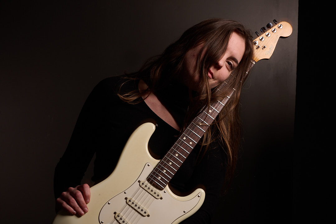 Photo of Ali McGuirk holding an electric guitar