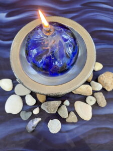 Photo of blue candle among rocks and sea shells