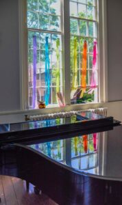 Rainbow-colored streamers hang in the window behind the piano