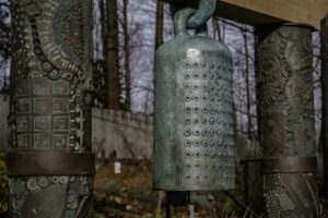 Closeup of the top of the bronze labyrinth bell, suspended between two embellished clay columns